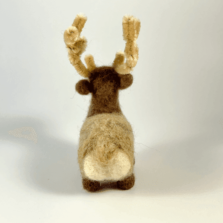 A needle-felted elk with pipe cleaner antlers faces away from the camera showing its round white bottom and blond tail.
